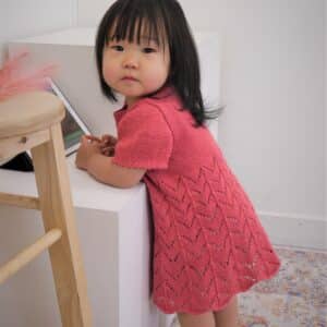 Young girl wears Pelong Pelong knitted dress in coral